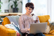 © leszekglasner - Relaxed woman using laptop sitting on sofa home