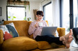 © leszekglasner - Relaxed woman using laptop sitting on sofa home