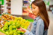Girl in supermarket chooses fresh fruits and vegetables