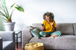 canvas print picture - Excited happy young black woman holding smart phone device sitting on sofa at home - Happy satisfied female looking at mobile smartphone screen gesturing yes with clenched fist - Technology concept