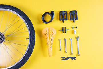 Set of different bicycle tools and parts on yellow background, flat lay. Space for text.