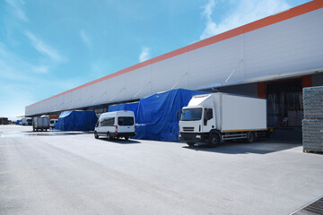 white truck in front of the warehouse, a loading truck