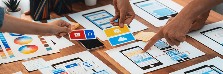 Poster - Panorama shot of front-end developer team brainstorming UI and UX designs for mobile app on paper wireframe interface. User interface development team planning for user-friendly UI design. Scrutinize