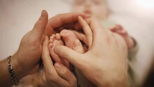 Baby Feet In Mother And Father Hands. Tiny Newborn Baby's Feet On Female And Male Hands Close Up. Mom, Dad And His Child. Happy Family Concept. Beautiful Conceptual Video Of Maternity And Fatherhood