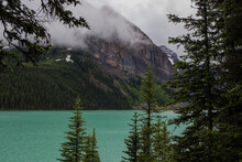 Amazing Lake Louise In Banff National Park, Alberta, Canada. Cloudy Day After Rain. Blue Lake Water And Misty Mountins. Famous Place For Traveling. Idyllic Summer Landscape.