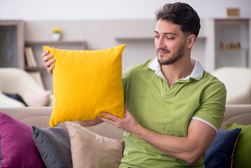 Poster - Young man with a lot of pillows sitting on the sofa