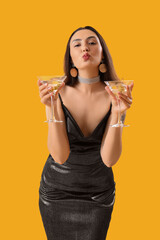 Wall Mural - Beautiful woman with martini blowing kiss on orange background