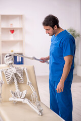 Wall Mural - Young male doctor and skeleton patient in the clinic