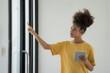 © Songsak C - Happy African-American businesswoman using a digital tablet and pointing a finger at a glass window.