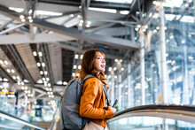 Young Asian Woman In International Airport Terminal Or Modern Train Station. Backpacker Passenger Female Commuter Walking On Escalator