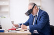 © Elnur - Old male employee wearing virtual glasses at workplace