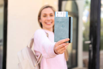 Wall Mural - Young blonde woman holding a passport at outdoors