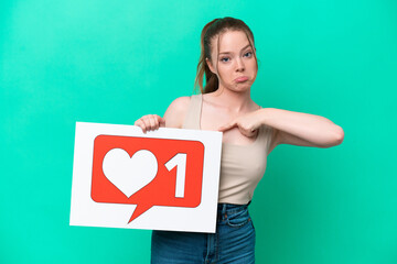 Wall Mural - Young caucasian woman isolated on green background holding a placard with Like icon and pointing it