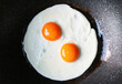Top view of pair of sunny side up eggs being fried in a pan