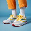 legs and feet wearing sneakers in yellow trousers isolated on plain blue studio background, made with generative ai