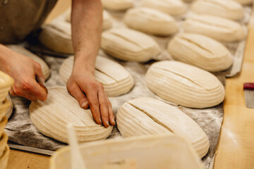 baker finishing sourdough loaves before putting them in the oven professional kitchen