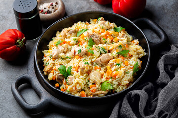 Wall Mural - Chicken Pilaf, pilau or biryani. Dish made of long-grain rice, chicken meat and vegetables, onion, carrots, spices and parsley. Eastern cuisine. Dark grey background.