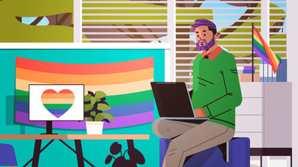 Wall Mural - gay sitting at workplace and using laptop lgbt rainbow flag transgender love generation Z concept office interior