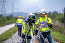 Surveyor Engineers Team Wearing Safety Uniform,helmet And Blueprint Document Checking Inspection By Theodolite To Measurement Position On Railway Construction Site Is Industry Transportation Concept.