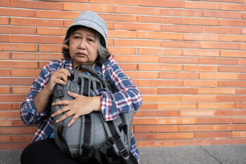 Poor tired stressed depressed elderly Asian woman homeless sitting on the street in the shadow of the building and begging for help and money, Elderly Asian woman abandoned concept