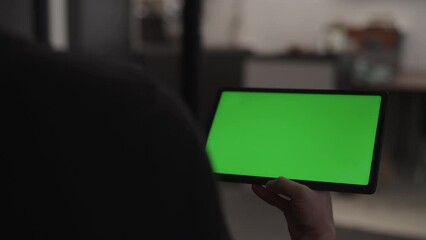 Wall Mural - Man indoors on a chair with tablet pc with green screen