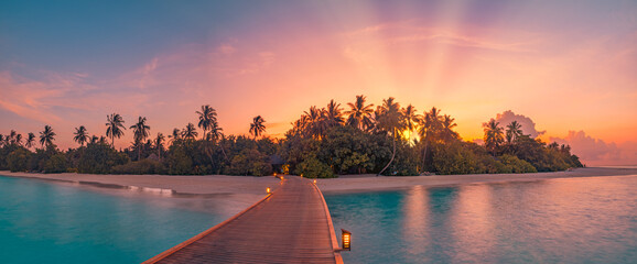 Wall Mural - Beautiful sunset beach coast. Colorful sky clouds sun rays over palm trees silhouette. Panoramic island landscape, calm sea reflections relax tropical paradise. Wooden pier path led lights in resort