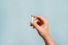 White Pill In Female Hand On Blue Background, Taking Your Medication