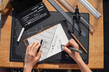 Architect and designer working accurately on a project drawing sketches and technical drafts on paper using professional tools like rulers compass and triangle logo design top view over the shoulder