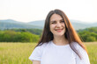 © Zarina Lukash - Portrait of a 30-year-old European woman smiling while looking at the camera while walking in nature in a field.