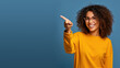Leinwandbild Motiv Beautiful young black woman pointing up to copy space and smiling, happy, Pretty girl act like satisfied at the product, use for advertising , isolated on blue background