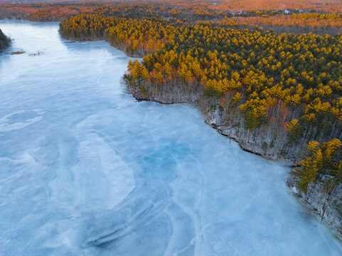 aerial view of frozen river and forest under sunlight