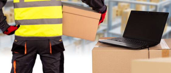 Poster - Laptop on boxes. Storekeeper with his back to camera. Framed worker. Man with box in warehouse. Laptop on parcels. Cardboard boxes inside storage. Fulfillment industry. Warehouse software concept