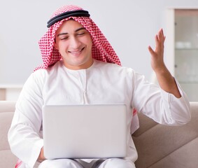 Wall Mural - Young arab businessman working with laptop on sofa