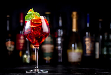 Sticker - Red sangria summer alcoholic drink with red spanish wine, peach, plum, orange, lime and ice. Black bar counter background, steel bar tools and bottles