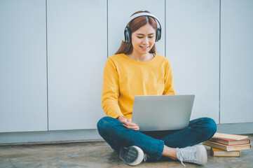 Wall Mural - young student wearing headphones studies online, distance learning, and keeps up to date on the global coronavirus pandemic.