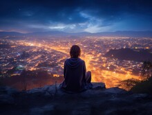 A Girl Sits On A Hillside At Dusk, Looking Out Over A Bustling City.