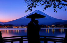 A Silhouette Of A Couple Standing With Umbrellas On A Bridge Under The Shadow Of Sakura To View Mt. Fuji During Twilight.