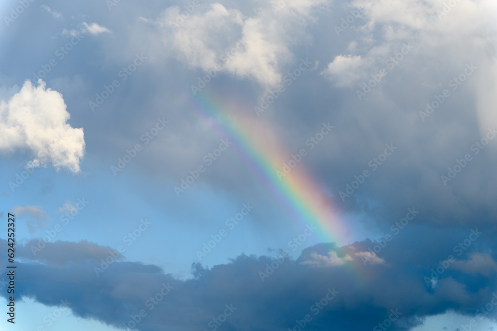 Amazing bright rainbow in a beautiful blue cloudy sky after rain and ...