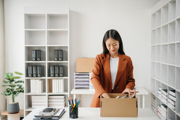 Happy and excited young beautiful Asian woman office worker celebrating her resignation, carrying her personal stuff. leaving job, changing or company.in nodern office