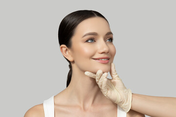 Wall Mural - A beautiful girl makes an injection of botox, on a gray background