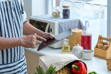 Male hands with digital recipe. Healthy salad on digital tablet. Vegetable and Shopping bag.