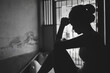 © Tinnakorn - Silhouette of Depressed young woman near window at home, closeup in the dark room. domestic violence, violence against womenBlack and white photo.