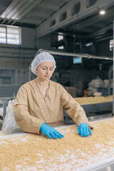 Wall Mural - Worker woman for visual control quality raw pine nuts without shell on automatic conveyor belt for transporting. Concept food industry, factory production line