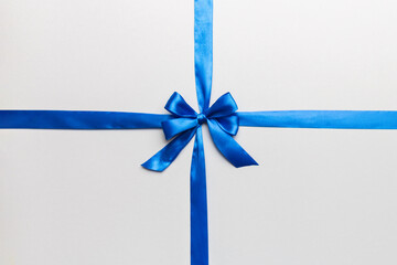 Top view of blue ribbon rolled and blue bow isolated on colored background. Flat lay with copy space