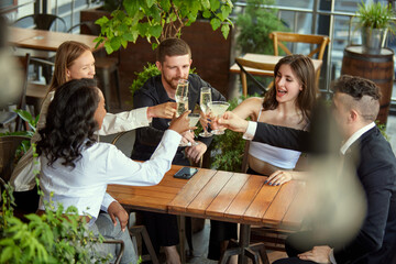 Group of employees, colleagues meeting at cafe after work, celebrating successful deal, drinking champagne and cocktails. Concept of leisure time, business, communication, fun, alcohol drink