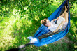 © puhimec - Cute girl reading a book in a hammock in the garden.