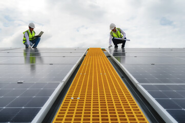 Young Engineers and Specialist Technicians Check Quality of Installing Solar Photovoltaic Panels and Use App Technology Checking Accumulated power generation from Solar Panel on Laptop.