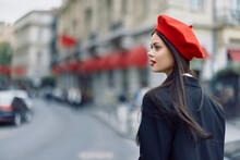 Fashion Woman Portrait Beauty Standing On The Street In Front Of The City In Stylish Clothes With Red Lips And Red Beret, Travel, Cinematic Color, Retro Vintage Style, Urban Fashion Lifestyle.