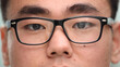 Close-up of a focused Asian businessman, wears glasses to reduce eye strain