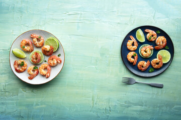 Shrimps, overhead flat lay shot with copy space. Cooked shrimp with lime, two plates, shot from the top on a teal blue background